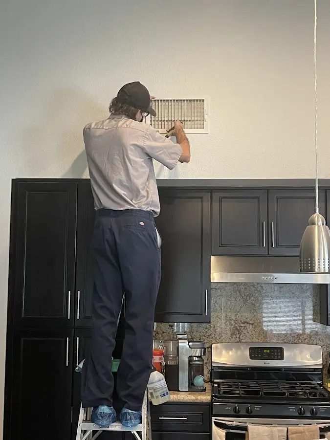 Technician inspecting an air vent during HVAC service in McCook
